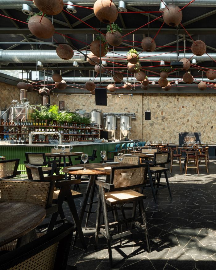 Woven chairs around small tables near the green-coloured bar.