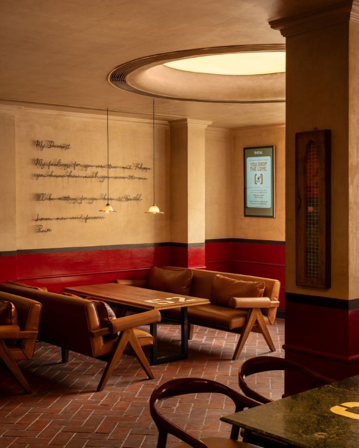 A handwritten love letter in cursive script on the wall in a room with lounge chairs and a brick floor