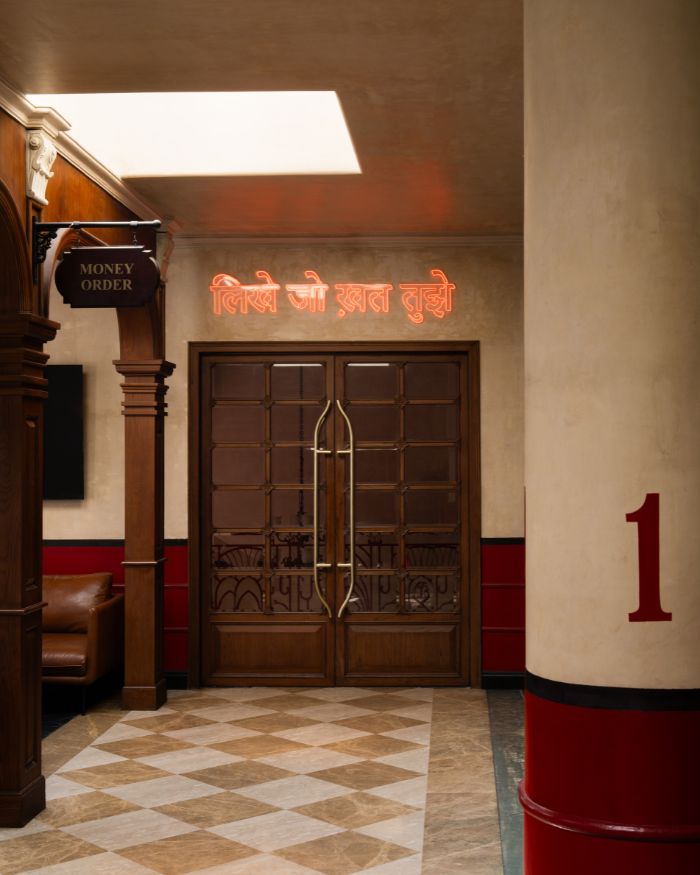 A Hindi couplet glows above the private dining door in a space with a checkerboard floor