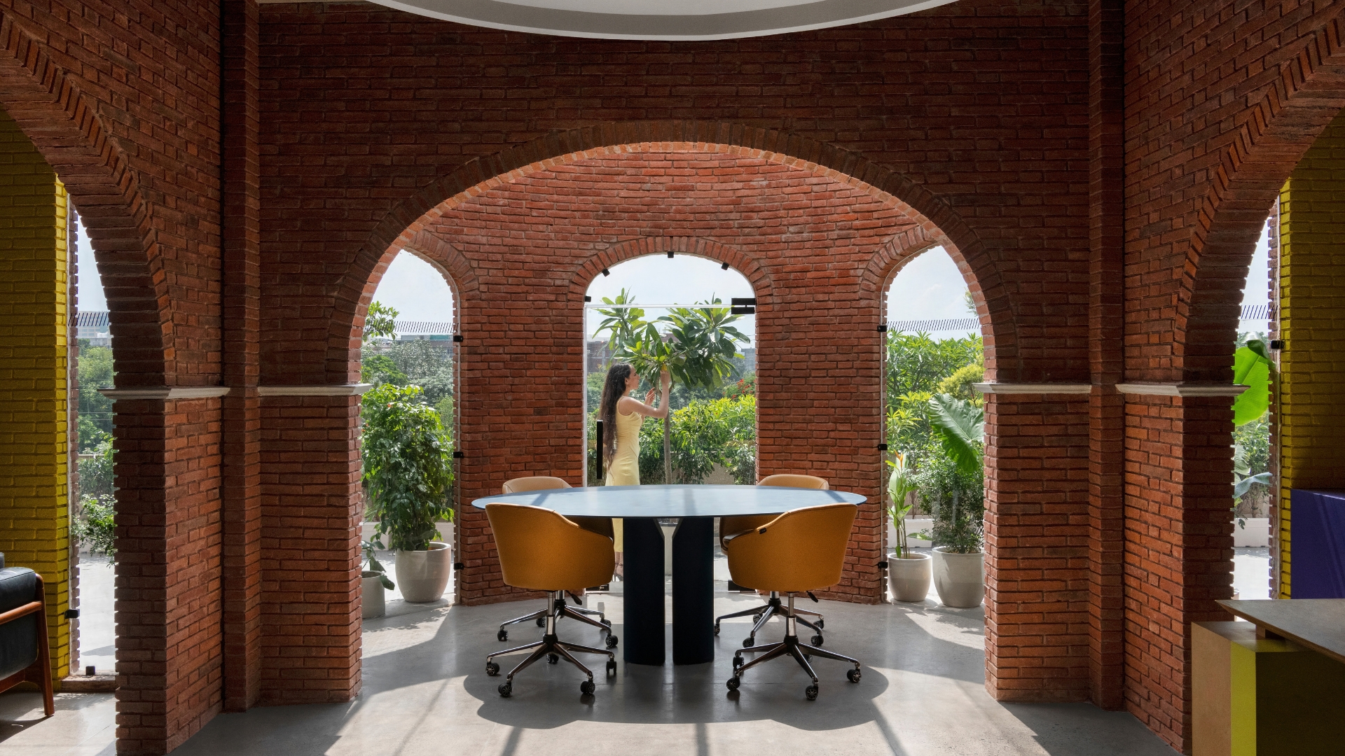 The Sunroom with a conference table beneath the brick arches and terrace greenery outside