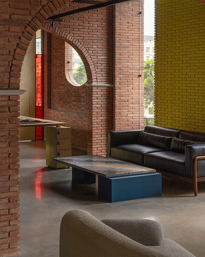 A brick arch leads straight out to the terrace conference table, its mustard chairs set against a wall of greenery