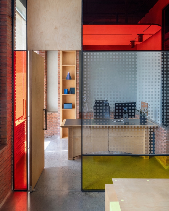 Black-framed glass partitions in red and yellow screening a private desk without shutting it off entirely