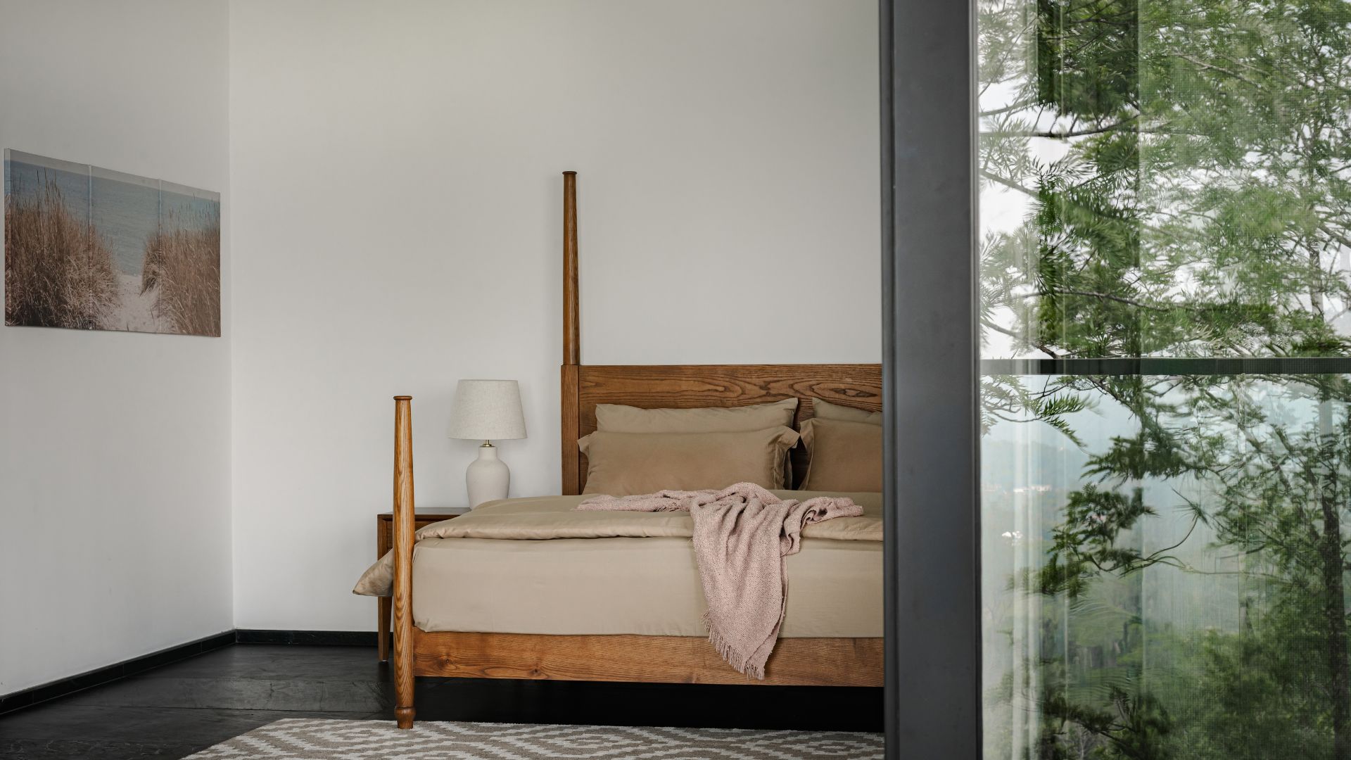 Black marble floor anchors the bedroom, paired with a bed, side tables and a rug, with a sliding door reflecting the green expanse outside