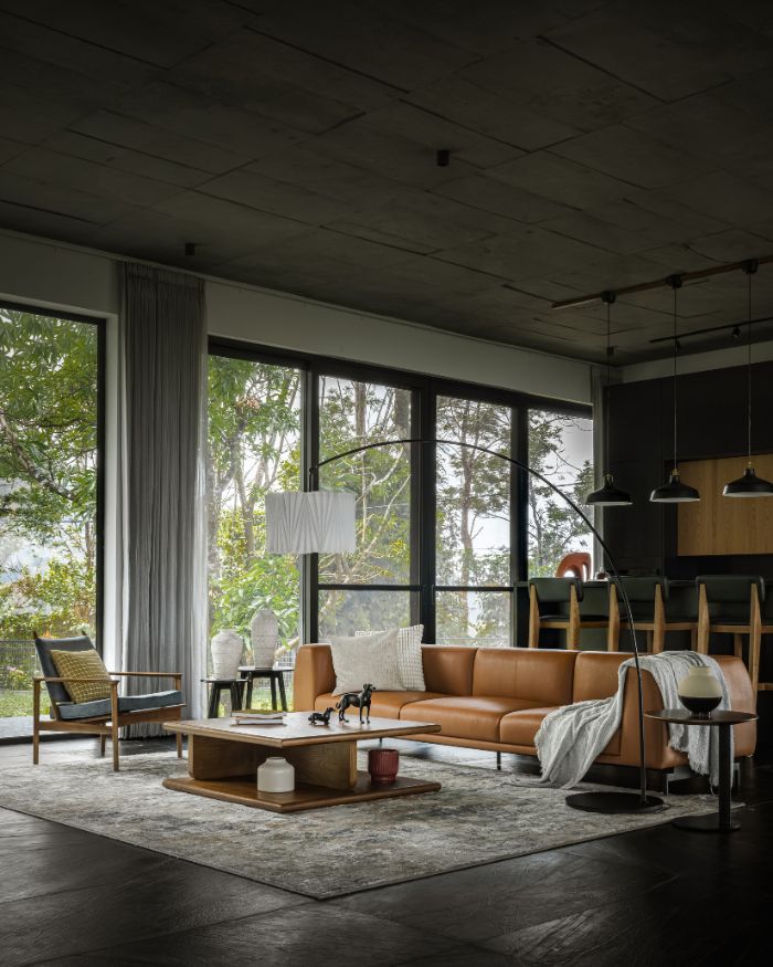 Black marble flooring grounds the space, paired with a customised leather sofa and centre table, a rug and a floor lamp