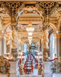 Morning light floods the New York Café through tall arched
windows, catching gilded stucco and crystal as rows of tables line the nave, the marble stair and raised gallery closing the perspective; Photographs courtesy Anantara New York Palace Budapest Hotel