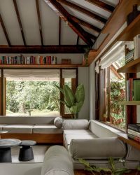 The living room’s walls are lined with teakwood shelves, filled with the homeowners’ books that add colour and character to the space; Photography by Manthan Yadav