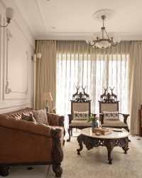 Living room featuring two deer-crowned armchairs against sheer curtains and a brown leather sofa, with wall mouldings and ceiling medallions in POP and paint, complemented by a Hands Carpet floor rug from HomeSaas, Lajpat Nagar; Photography by Tarang Goyal