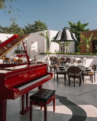 Dubbed Chowk, the open courtyard space is anchored by a gleaming red piano sitting underneath a tree. The black-and-white striped floating
umbrellas are supported by Araish plastered planters, their looming form inspired by Rajasthan’s ceremonial umbrellas; Photography by Ishita Sitwala